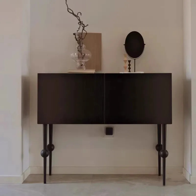 Dark wooden console table with decorative items against a plain wall.