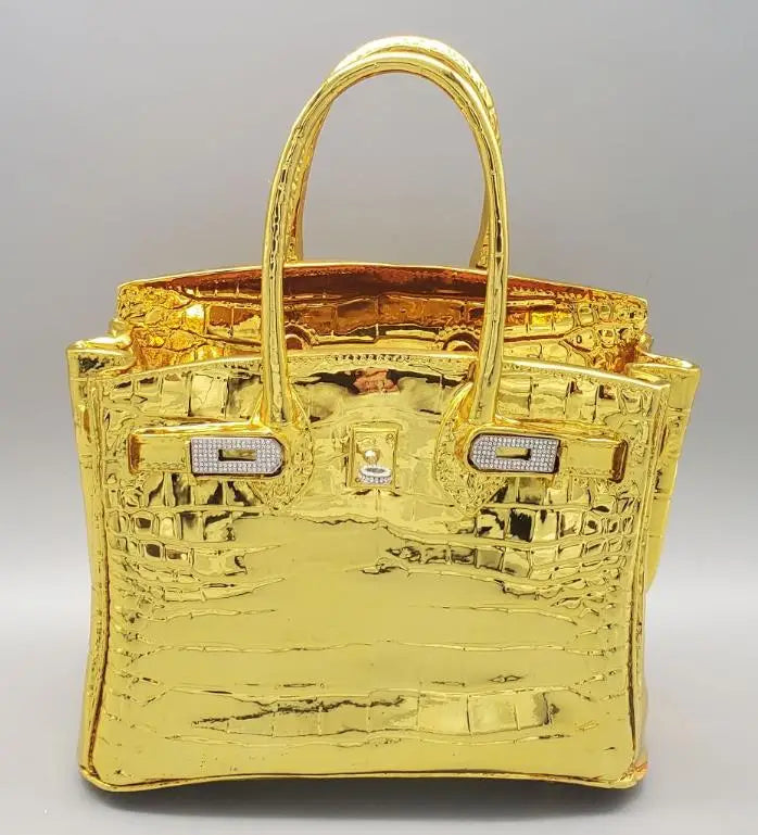 Gold handbag with crocodile pattern on a grey background Sculptural vase for dried flowers