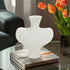 White textured vase on a stack of books with orange tulips in the background