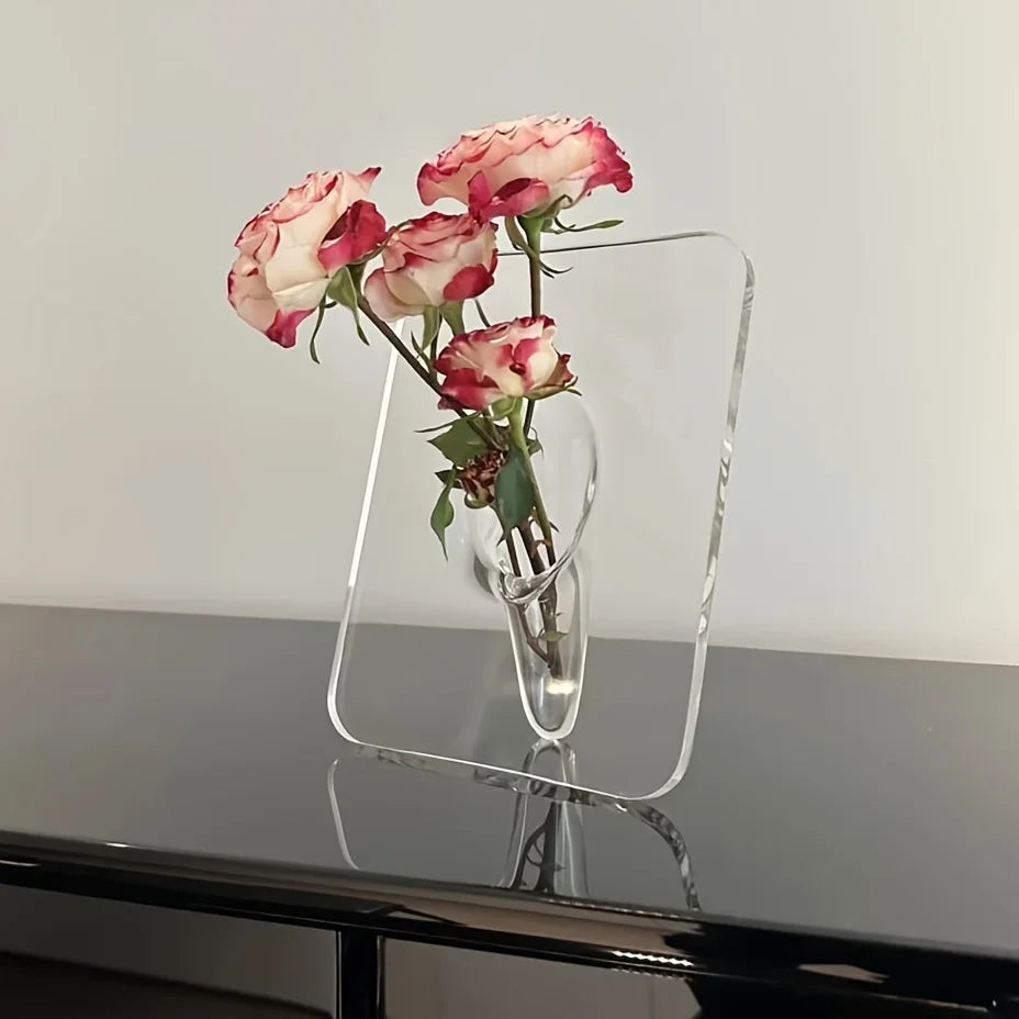 Clear glass vase with pink roses on a reflective surface
