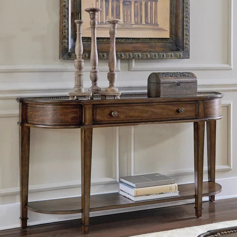 Wooden console table with decorative items against a wall with a framed picture.