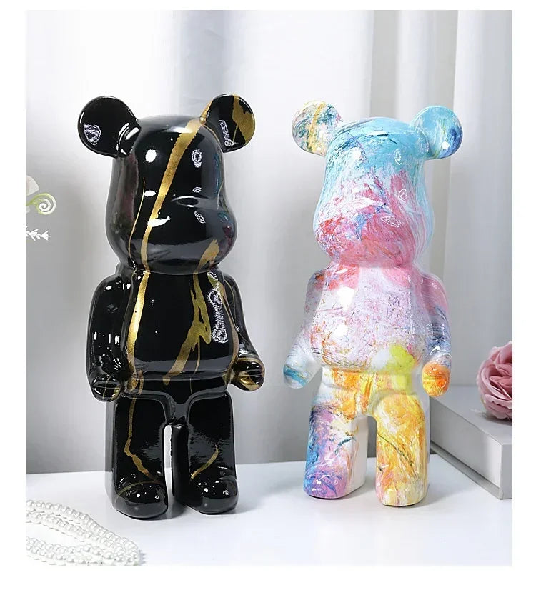 Two stylized bear figures, one black with gold accents and the other multicolored tie-dye, on a white surface.