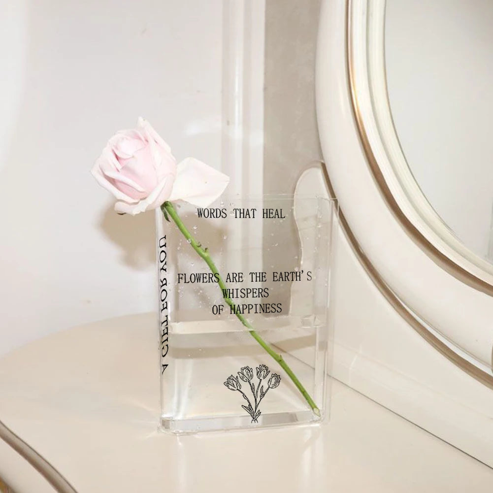 Clear vase with a pink rose and text on a white surface