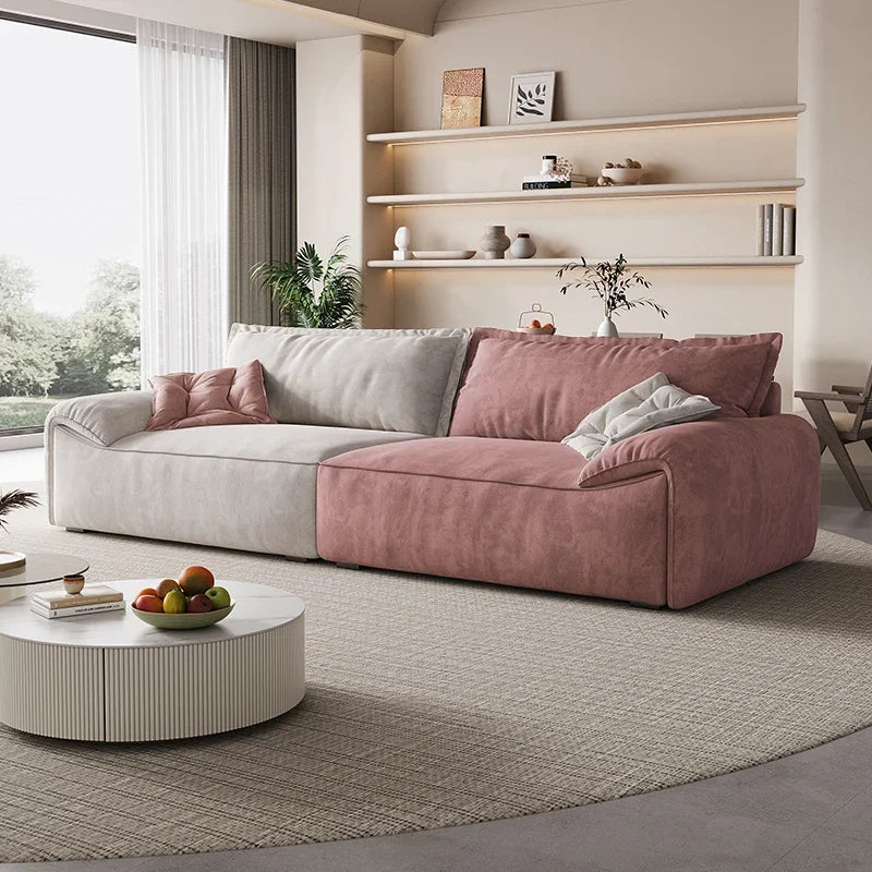 Modern living room with a pink and gray sectional sofa, round coffee table, and decorative elements.