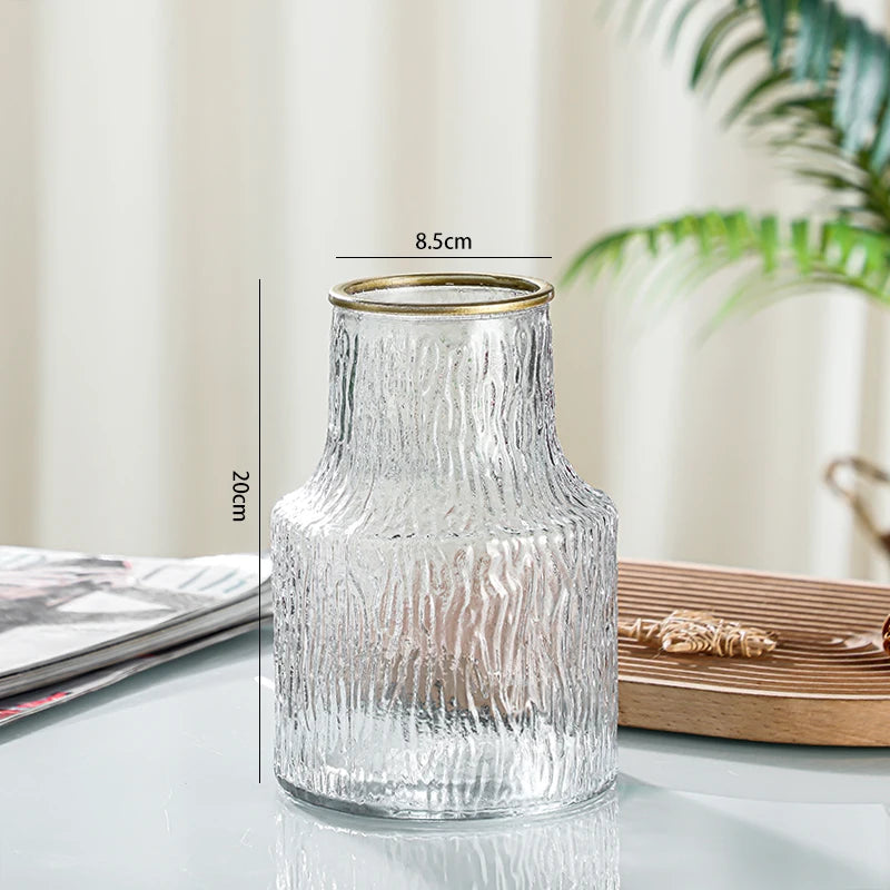 Clear glass vase with gold rim on a reflective surface, with measurements indicated.
