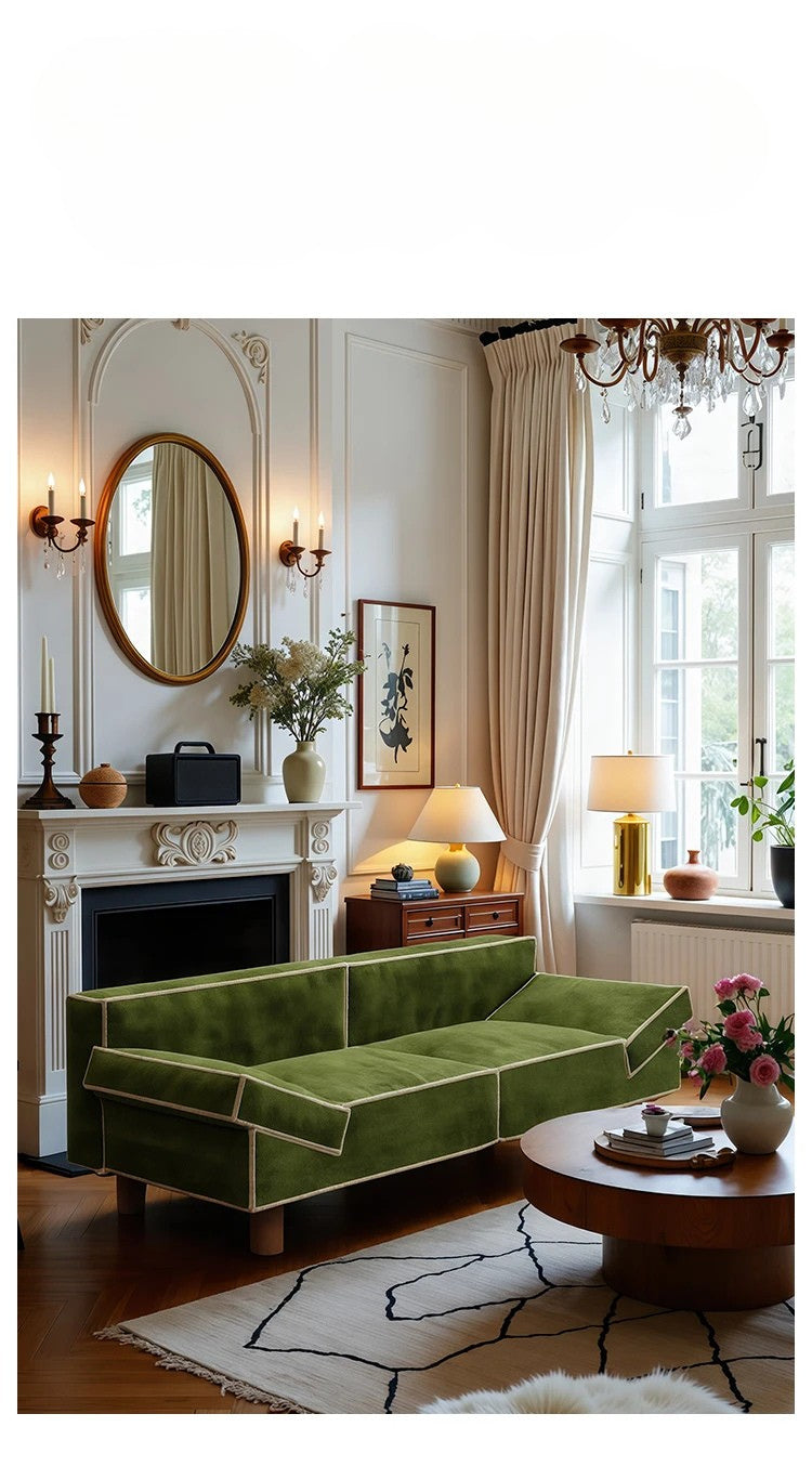 Green sofa in a living room with a fireplace, mirror, and decorative items.