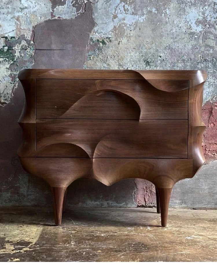 Wooden dresser with wavy design against a textured wall