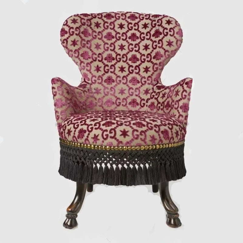 Patterned armchair with decorative fringe on a white background