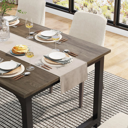 Dining table set with plates, glasses, and cutlery on a striped rug.