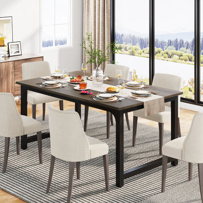 Dining room with a long dark wooden table set for a meal, surrounded by white chairs. Large windows show a scenic view.