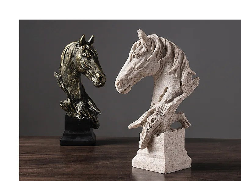 Two horse head sculptures, one bronze and one stone-like, on a wooden surface with a dark background.