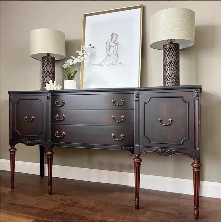 Dark wood sideboard with lamps and artwork in a room setting