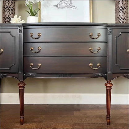 Dark wood sideboard with gold handles against a neutral wall.