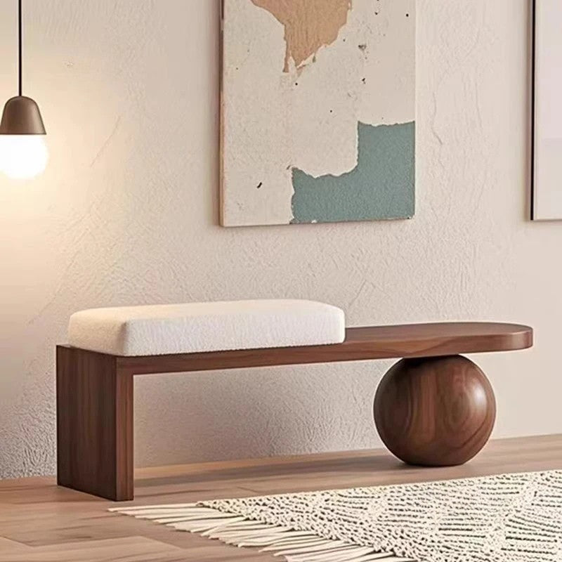 Wooden bench with a spherical base in a room with a textured wall and abstract art.