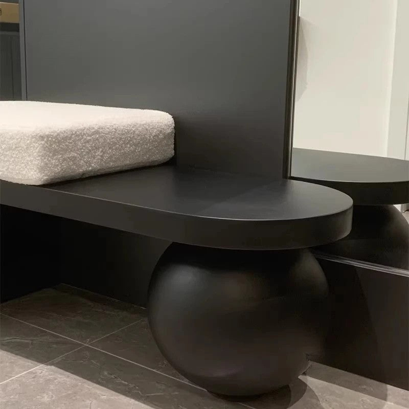 Modern black console table with spherical base against a gray wall.