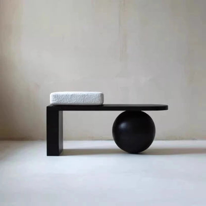 Minimalist black table with a sphere and cushion on a plain background