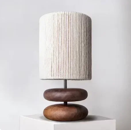 Table lamp with a textured white shade and wooden base on a light gray background