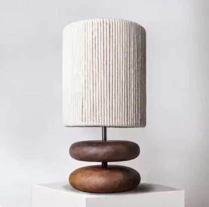 Table lamp with a textured white shade and wooden base on a light gray background