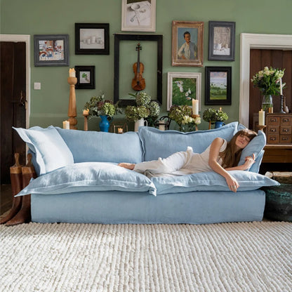 Woman lying on a blue sofa in a room with decorative elements and a green wall.
