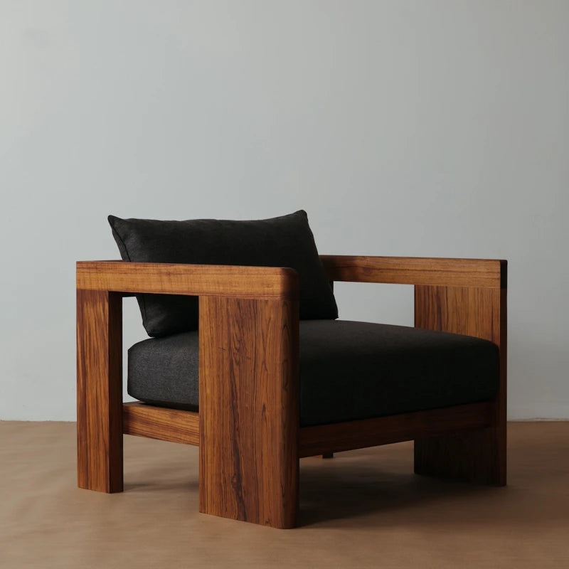 Wooden armchair with dark cushions against a plain background