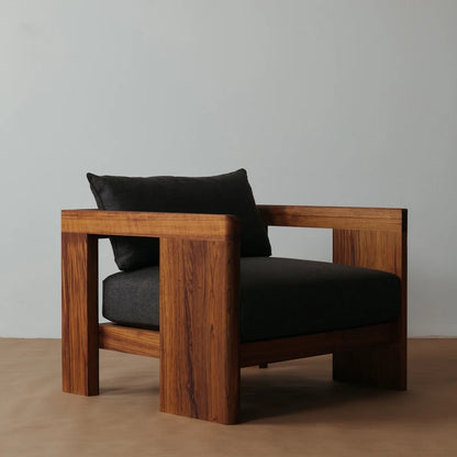 Wooden armchair with dark cushions against a plain background