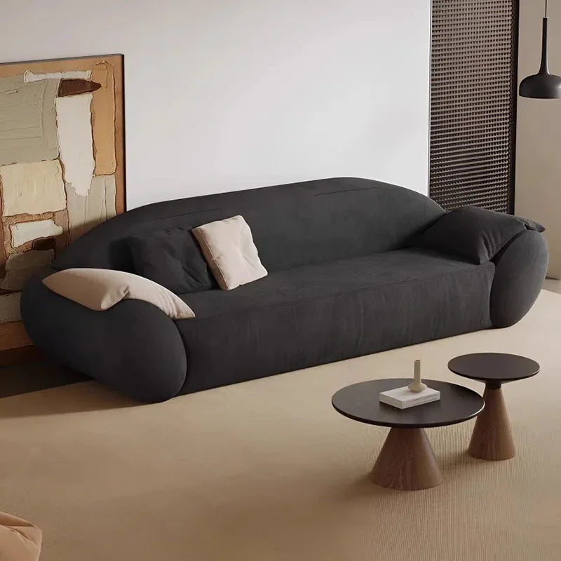 Modern black sofa in a minimalistic living room with two small tables.