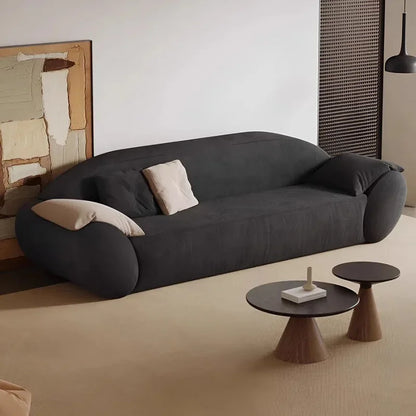 Modern black sofa in a minimalistic living room with two small tables.