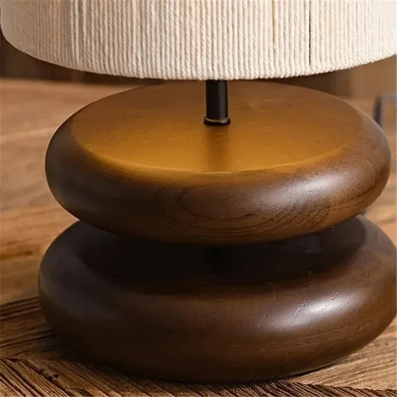 Wooden lamp base with a beige lampshade on a wooden surface