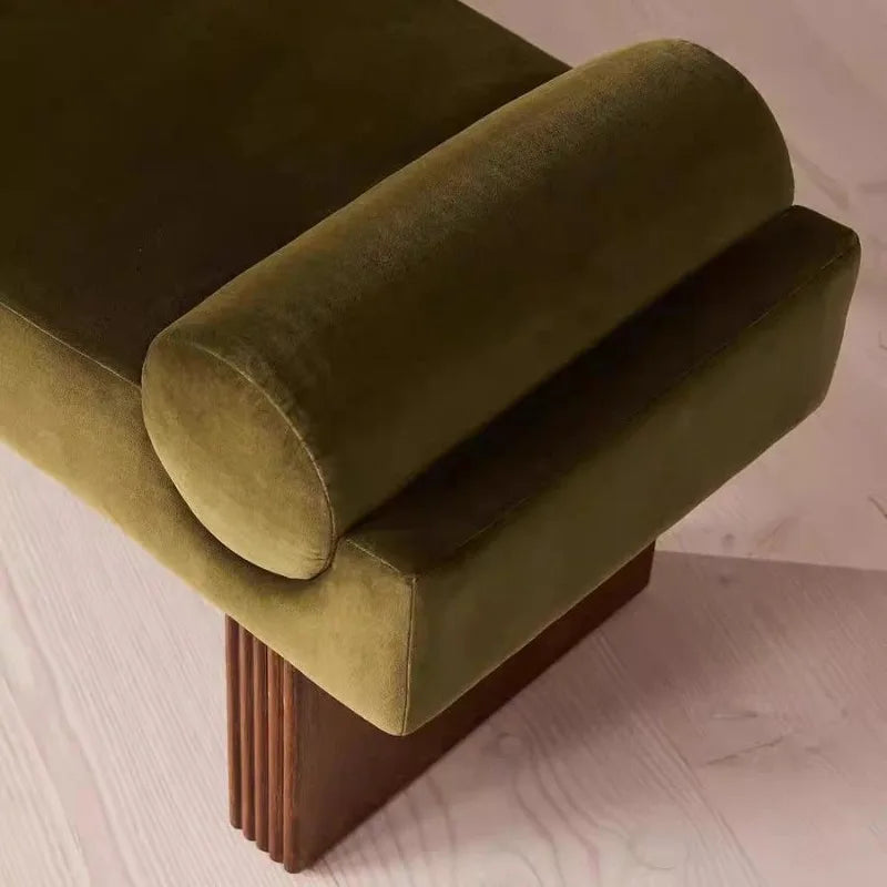 Green upholstered bench with wooden legs on a light wood floor.