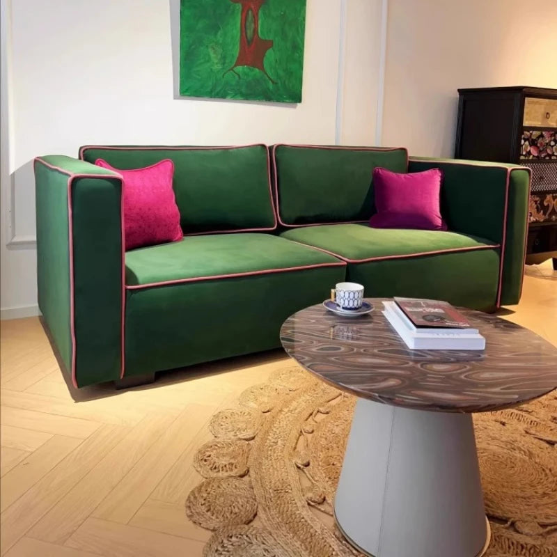 Green sectional sofa with pink cushions in a living room setting.