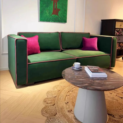 Green sectional sofa with pink cushions in a living room setting.