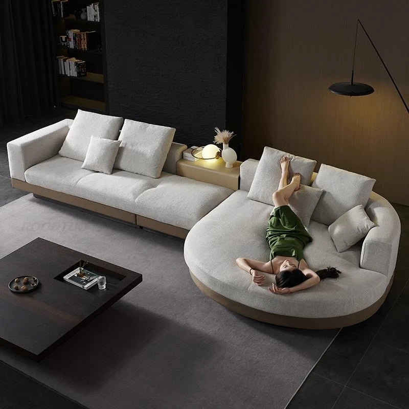 Modern living room with a large gray sectional sofa and a person lying on it.