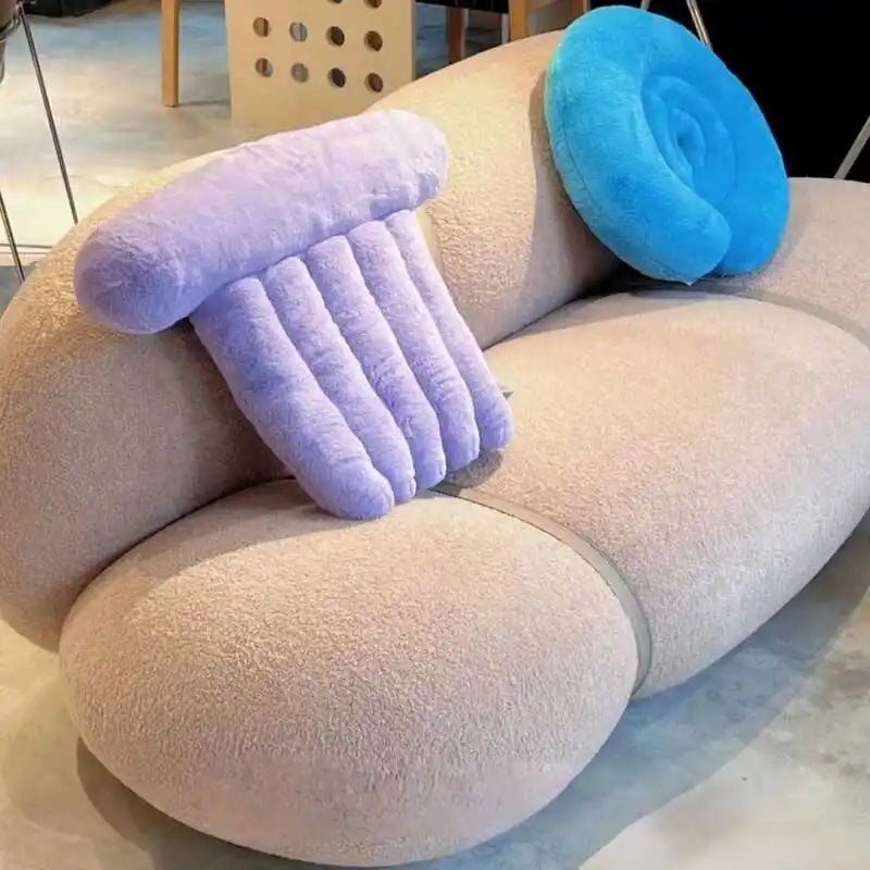 Three colorful inflatable neck pillows on a beige sofa.