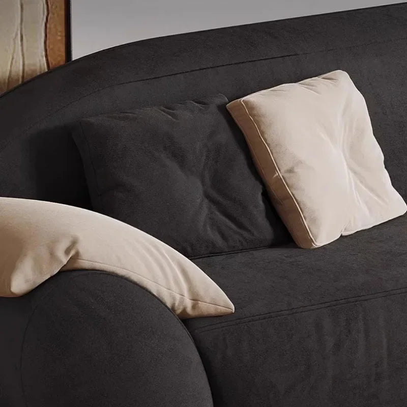 Dark gray sofa with beige and dark gray pillows against a neutral background