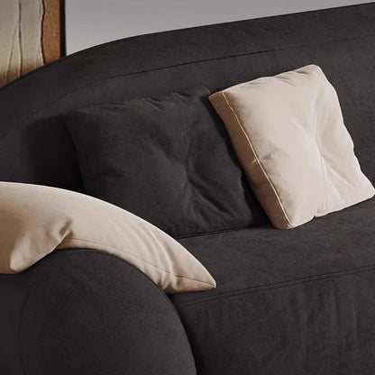 Dark gray sofa with beige and dark gray pillows against a neutral background