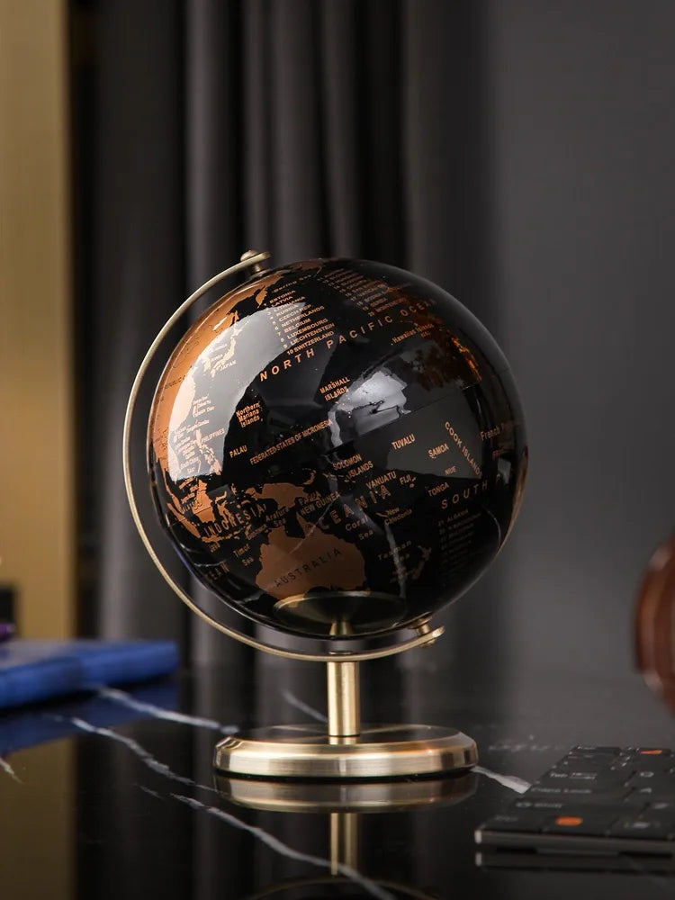 Black and gold globe on a desk with blurred background