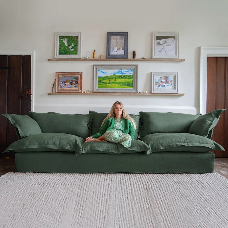 Woman sitting on a green sofa in a living room with framed pictures on the wall.