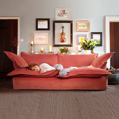 Person lying on a large red sofa in a living room with decorative elements.