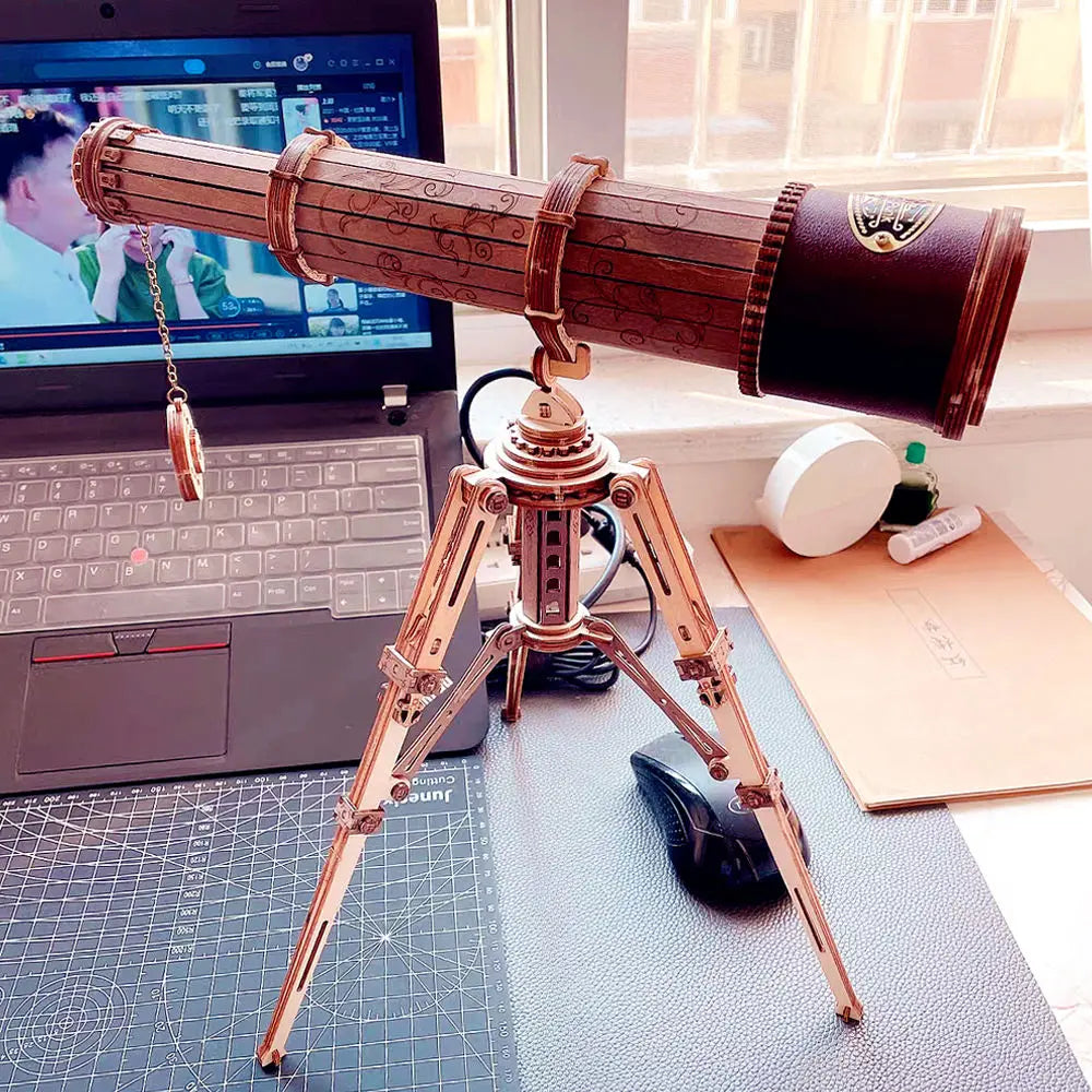 Vintage-style telescope on a desk with a laptop in the background