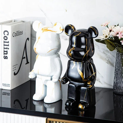 Two decorative bear statues, one white and one black with gold accents, on a reflective surface.