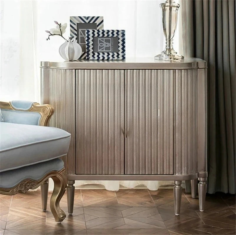 Decorative sideboard with a lamp and framed pictures in a room setting.