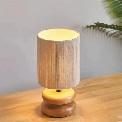 Wooden table lamp with a beige fabric shade on a wooden surface.