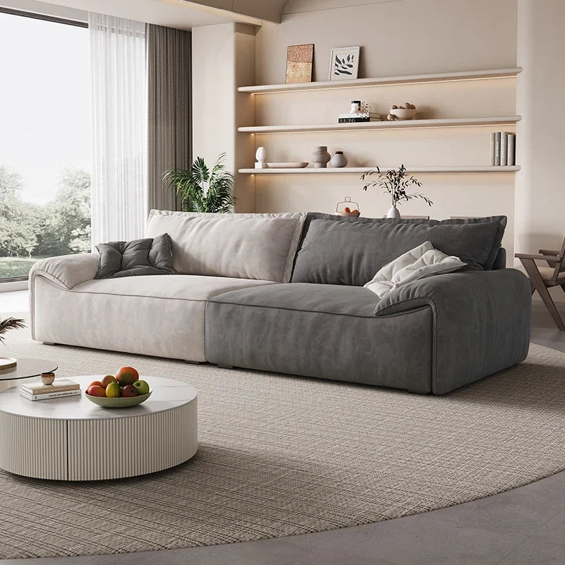 Modern living room with a gray sectional sofa, round coffee table, and shelves with decor.