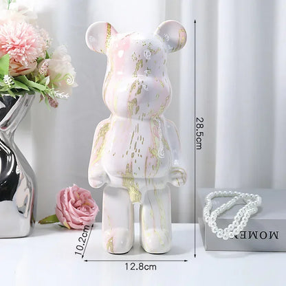 Decorative bear figure with measurements on a white surface with flowers and jewelry.