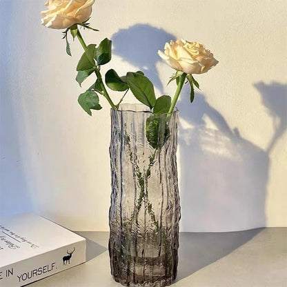 Glass vase with white roses on a light surface with a book in the background