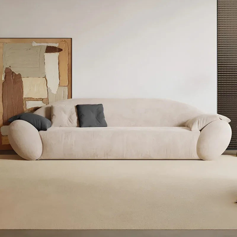 Beige sofa with cushions in a minimalistic room with abstract art on the wall.
