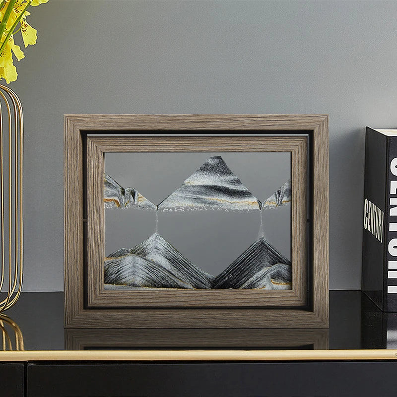 Framed artwork of mountains on a shelf with decorative items.