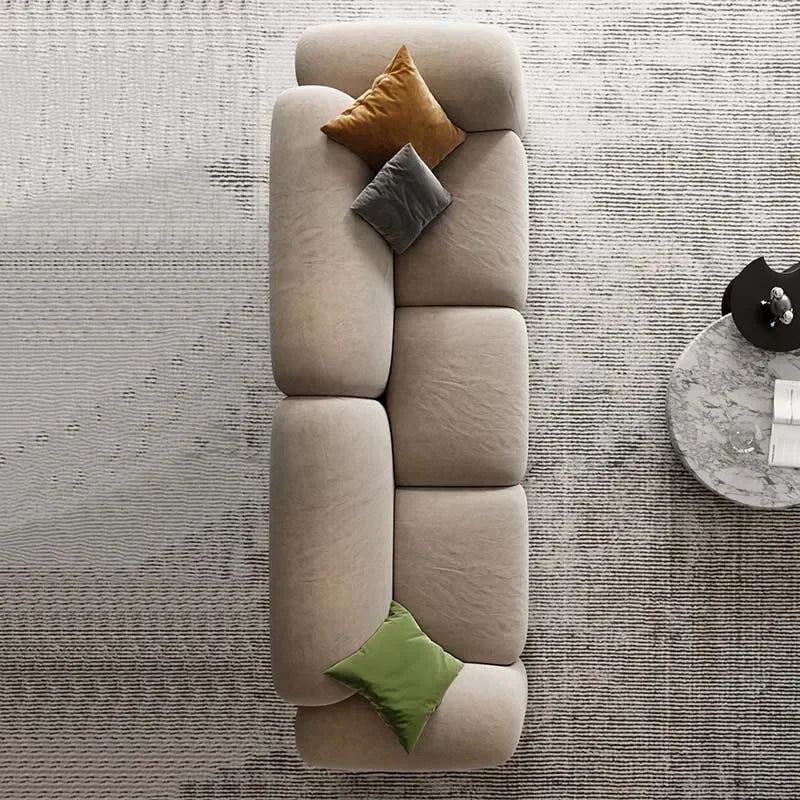 Beige sectional sofa with colorful cushions on a textured gray floor.