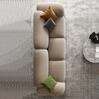 Beige sectional sofa with colorful cushions on a textured gray floor.