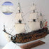 Model ship with white sails on a stand against a light background
